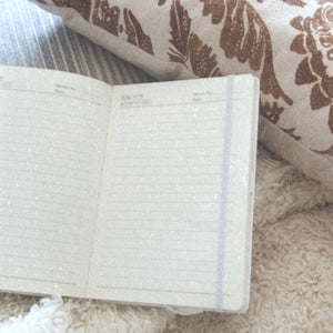 open lined notebook with fuzzy white blanket and brown floral pillow